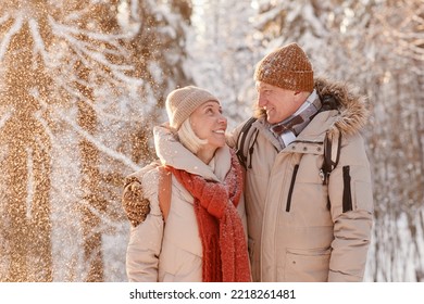 Waist up portrait of loving senior couple embracing in winter forest with snow falling - Powered by Shutterstock