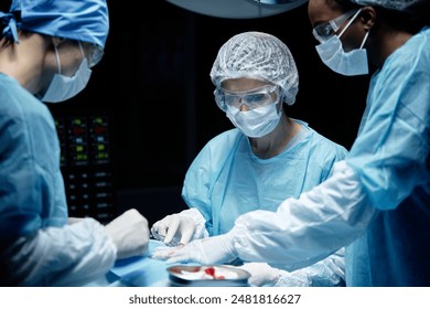 Waist up portrait of medical team with female surgeon performing operation in blue light at operating room - Powered by Shutterstock