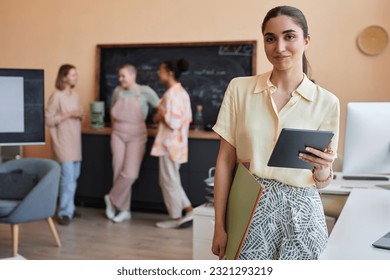 Waist up portrait of Middle Eastern young woman looking at camera standing in modern office setting, copy space - Powered by Shutterstock