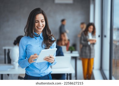 Waist up portrait modern business woman in the office with copy space. Female executive wearing businesswear standing outside modern meeting room and checking data on tablet. - Shutterstock ID 2258627215