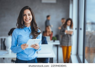 Waist up portrait modern business woman in the office with copy space. Female executive wearing businesswear standing outside modern meeting room and checking data on tablet. - Shutterstock ID 2259403041