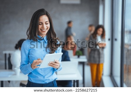Waist up portrait modern business woman in the office with copy space. Female executive wearing businesswear standing outside modern meeting room and checking data on tablet.