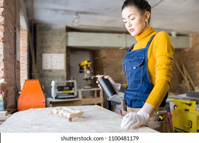 Waist Up Portrait Of Modern Young Woman Spray Painting Wood While Working In Carpenters Workshop, Copy Space