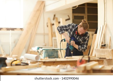 Waist up portrait of red haired carpenter working in joinery lit by sunlight, copy space