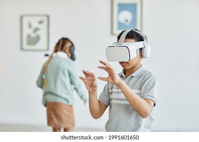 Waist up portrait of schoolboy wearing VR headset in art gallery while enjoying immersive experience, copy space - Powered by Shutterstock