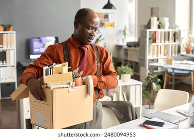 Waist up portrait of senior African American man holding box with personal items at workplace leaving office for late retirement copy space - Powered by Shutterstock