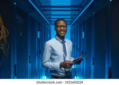 Waist up portrait of smiling African American man standing by server cabinet while working with supercomputer in data center and holding tablet, copy space - Powered by Shutterstock