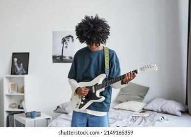 Waist up portrait of smiling African-American teenager playing electric guitar at home, copy space - Powered by Shutterstock