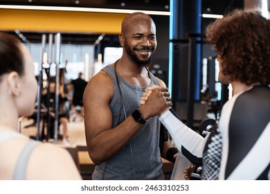 Waist up portrait of smiling Black fitness coach shaking hands with client meeting for training in gym - Powered by Shutterstock