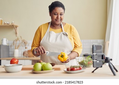 Waist Up Portrait Of Smiling Black Woman Cooking Healthy Meal In Kitchen And Recording Video With Smartphone, Copy Space