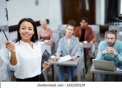 Waist Up Portrait Of Smiling Businesswoman Pointing At Whiteboard While Presenting Training Course For Students In Class, Copy Space