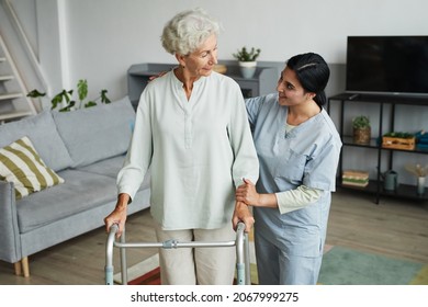 Waist up portrait of smiling female nurse helping senior woman using mobility walker in retirement home, copy space - Powered by Shutterstock