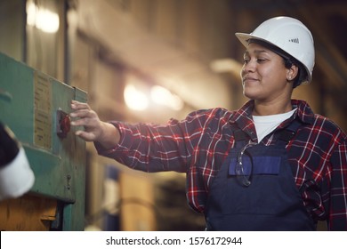 Waist Up Portrait Of Smiling Female Worker Pushing Red Button While Operating Machine Units At Production Plant, Copy Space