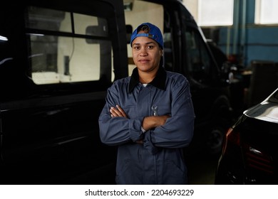 Waist Up Portrait Of Smiling Female Worker Standing With Arms Crossed In Car Factory Workshop And Looking At Camera