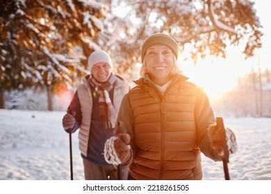 Waist up portrait of smiling mature couple enjoying Nordic walk in winter forest at sunset - Powered by Shutterstock