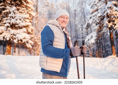 Waist up portrait of smiling mature man enjoying Nordic walk in winter forest at sunset, copy space - Powered by Shutterstock