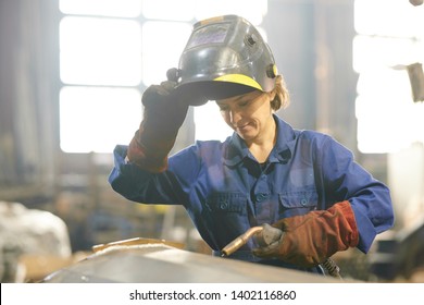 Waist up portrait of smiling woman welding metal while working at industrial plant, copy space - Powered by Shutterstock