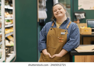 Waist up portrait of smiling young woman with Down syndrome enjoying work in supermarket and looking at camera with happiness copy space - Powered by Shutterstock