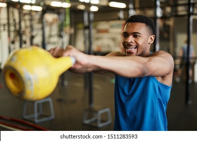 Waist up portrait of strong African-American man swinging kettlebell during cross workout in modern gym, copy space - Powered by Shutterstock