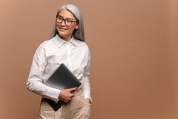 Waist Up Portrait Of Successful Confident Office Worker, Beautiful Woman In Formal Clothes Standing, Holding Closed Laptop And Looking Away With Toothy Smile. Studio Shot