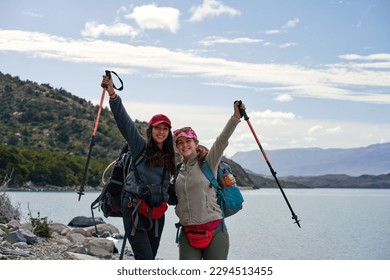 waist up portrait two Chilean young women hikers backpackers smiling embracing in Torres del Paine National Park
