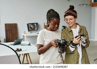 Waist up portrait of two female photographers holding cameras while working in photo studio, copy space - Powered by Shutterstock