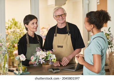 Waist up portrait of two florists talking to customer in flower shop, copy space - Powered by Shutterstock