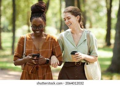 Waist up portrait of two smiling young women chatting outdoors while enjoying walk in park together - Powered by Shutterstock