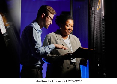 Waist Up Portrait Of Two System Administrators Using Computer In Dark Server Room Lit By Neon Light, Copy Space