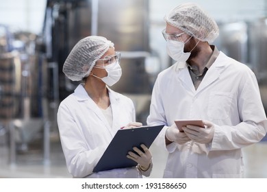 Waist up portrait of two workers wearing protective clothing while discussing production at modern chemical plant - Powered by Shutterstock