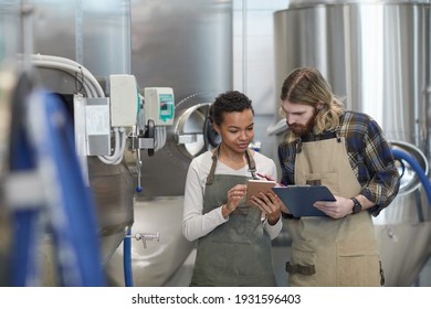 Waist up portrait of two young workers using digital tablet while inspecting production at modern craft brewery, copy space - Powered by Shutterstock