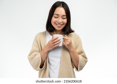 Waist up portrait view of the asian woman with short hair holding a cup of coffee isolated over white background 