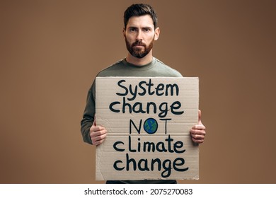 Waist Up Portrait View Of The Caucasian Worried Man Holding Carton Placard With System Change Not Climate Change Writing. Concept Of Nature Destruction And Eco Activism