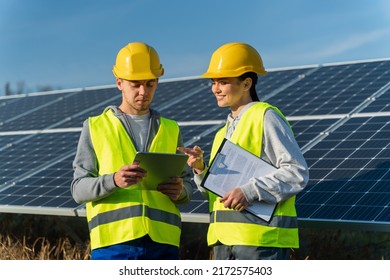 Waist Up Portrait View Of Male And Female Engineers In Hardhat Using Tablet While Working On Maintenance Of Contemporary Photovoltaic Panels On Solar Power Station 