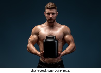 Waist Up Portrait View Of Sporty Shirtless Man Stretching To The Camera Jar With Healthy Drink, Whey Protein Isolated Over Black Studio Background 