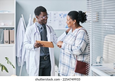 Waist up portrait of young African American doctor consulting female patient using digital tablet in clinic setting - Shutterstock ID 2254749933