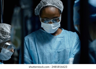 Waist up portrait of young African American female surgeon performing surgery in operating room in dramatic blue light - Powered by Shutterstock