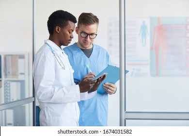 Waist Up Portrait Of Young African-American Doctor Talking To Supervisor In Medical Office Interior, Copy Space