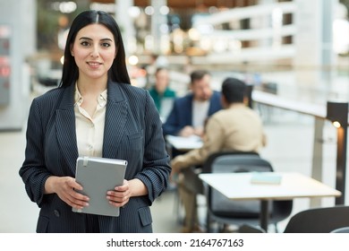 Waist Up Portrait Of Young Middle Eastern Businesswoman Holding Planner And Smiling At Camera In Modern Office Building Interior, Copy Space