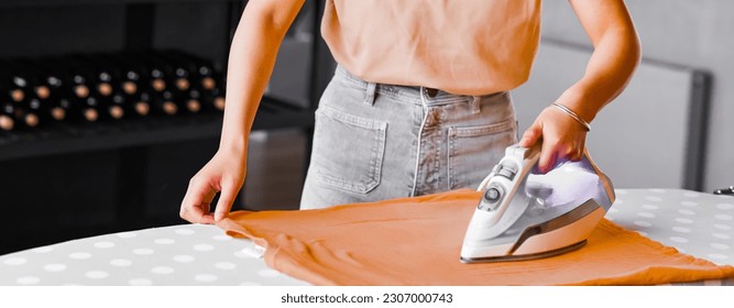 Waist up portrait of young woman ironing clothes at home and doing household chores, copy space - Shutterstock ID 2307000743