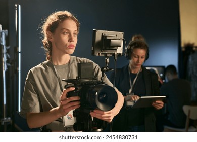 Waist up portrait of young woman setting up digital camera on set while directing video production copy space - Powered by Shutterstock