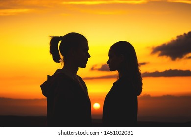 Waist Silhouettes Of A Young Millenial Couple In Love With A Man And A Girl Look At Each Other. Two Profile Of A Young Couple At Sunset