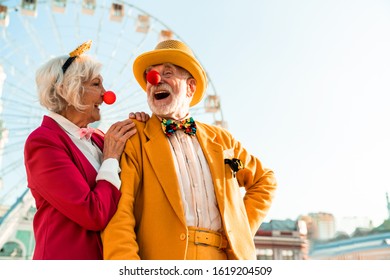 Waist Up Of Smiling Senior Couple Having Fun While Walking Near Ferris Wheel