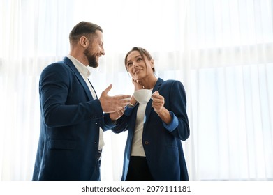 Waist-length portrait of diverse business partners, colleagues during a coffee break. Boss and employee flirting at work. The concept of partnership, teamwork and successful leadership at work - Shutterstock ID 2079111181
