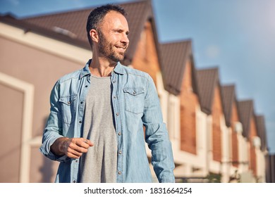 Waist-up photo of a successful young man standing in front of a newly-built house - Powered by Shutterstock