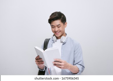 Waist-up portrait of Asian university student distracted from reading book and looking at camera with wide smile, isolated on white background