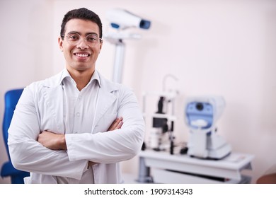 Waist-up Portrait Of A Cheerful Friendly Eye Doctor With His Arms Crossed Looking In Front Of Him