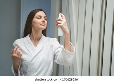 Waist-up Portrait Of A Female With Her Eyes Closed Hydrating Her Skin With A Facial Spray