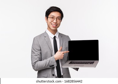 Waist-up Portrait Of Professional Handsome Asian Male Office Manager, Businessman Introduce His Chart Or Project, Showing Diagram On Laptop Screen, Pointing Computer And Smiling Camera