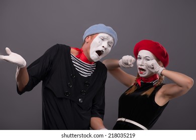 Waist-up Portrait Of Sad Mime Couple Crying With Closed Eyes, Female Mime Rubbing Her Eyes, Male Mime Breeding His Hands Isolated On Grey Background With Copy Place